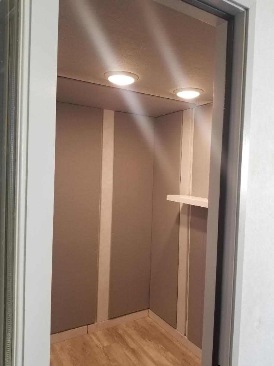 Cozy storage closet with recessed lighting and a shelf, featuring neutral walls and flooring.