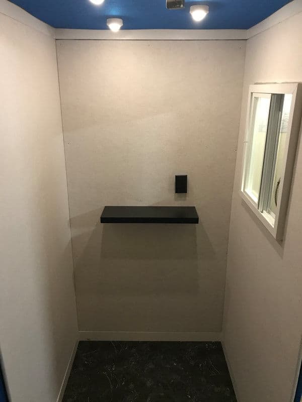 Empty room interior featuring a small black shelf and a window, with overhead lighting.