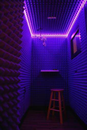 Soundproof recording booth with purple acoustic foam and LED lighting.