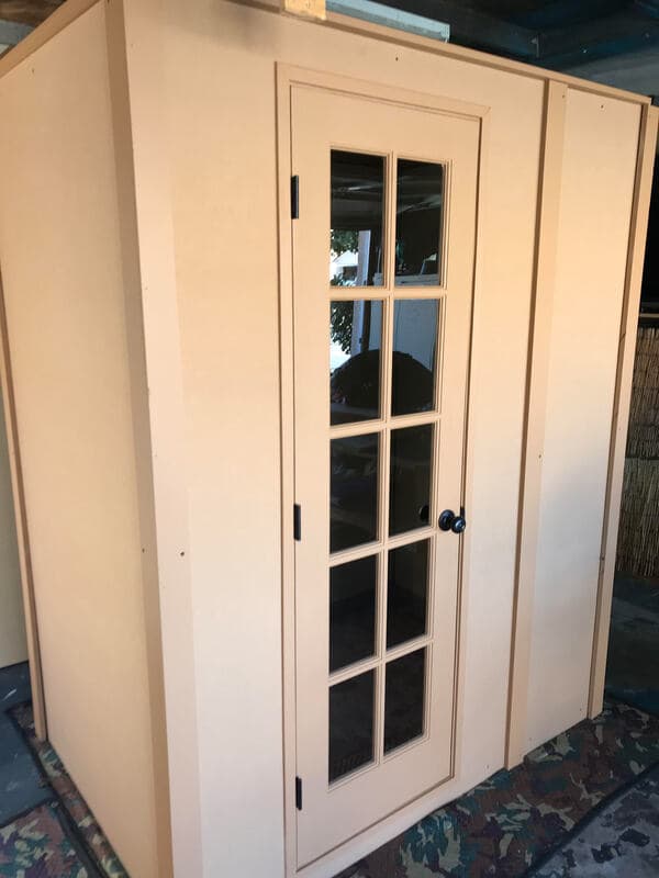 Stylish beige outdoor shed with glass-paneled door and modern design. Perfect for storage.