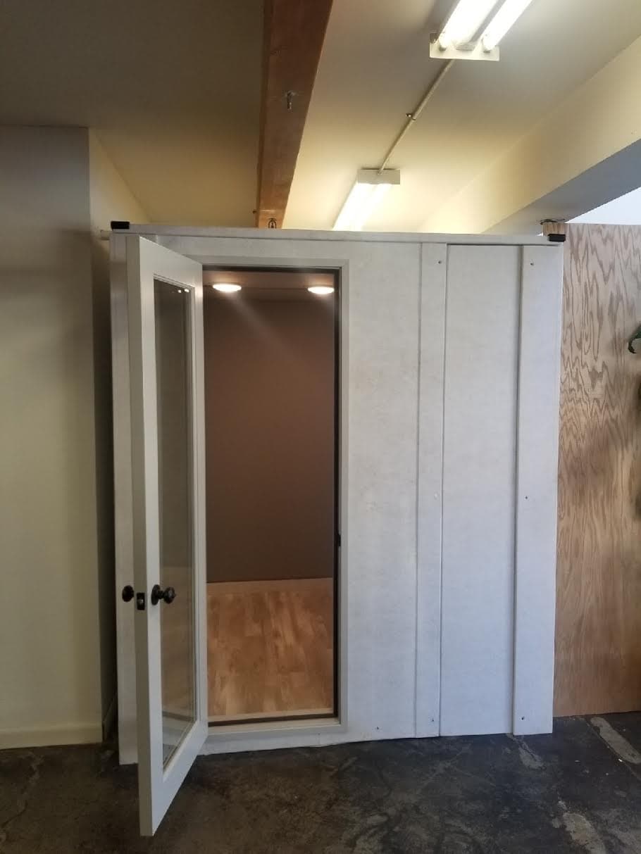 Modern modular office pod with an open door, situated in a well-lit interior space.