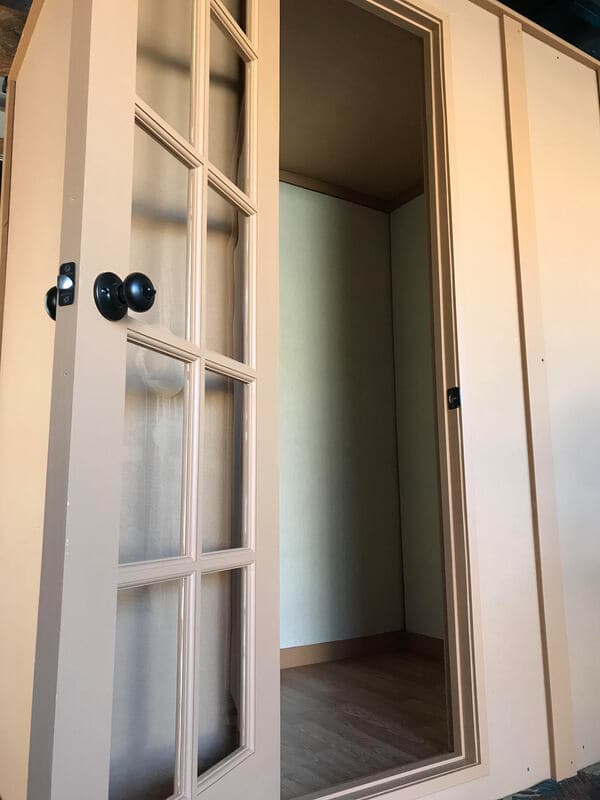 Peach-colored double doors leading to an empty interior room with wooden flooring.