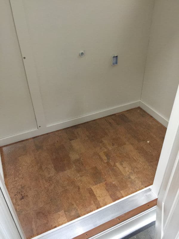 Interior view of a clean, empty closet with cork flooring and wall installation points.
