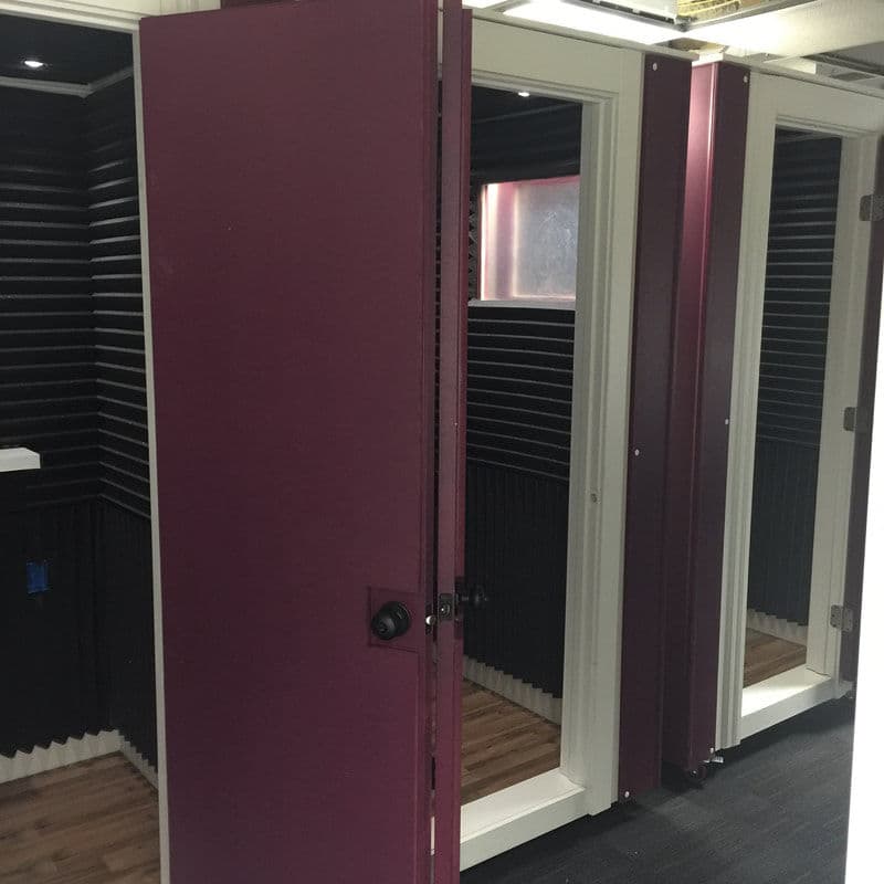 Soundproof recording studio with purple doors and black acoustic panels, featuring multiple booths.