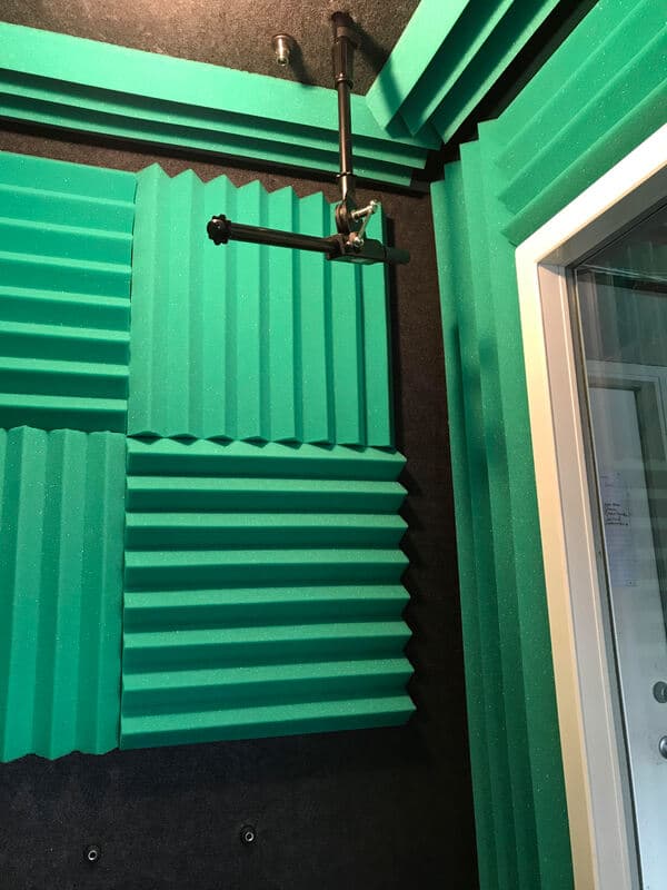 Acoustic treatment panels in recording studio with green soundproofing foam.