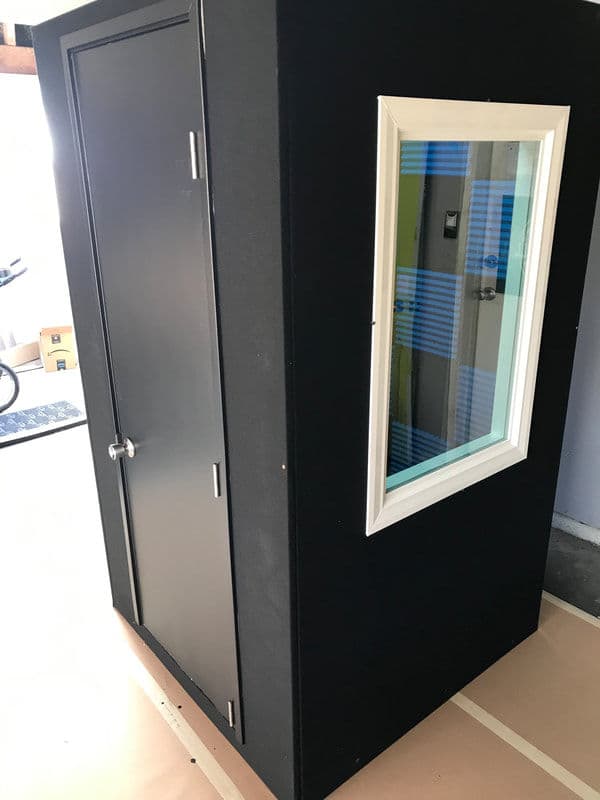 Black soundproof booth with a glass window, designed for audio recording or practice.