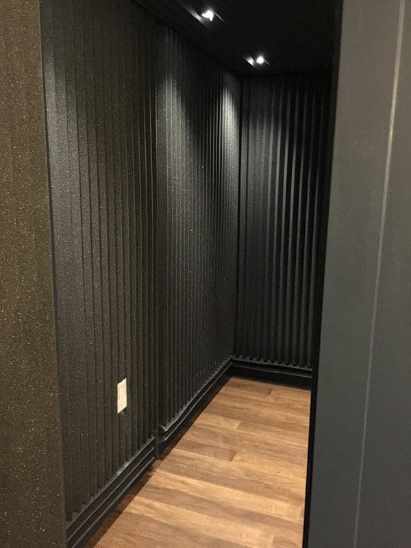 Interior view of a modern black soundproof room with textured walls and wooden floor.