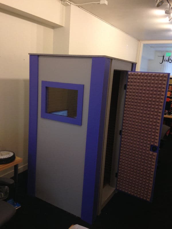 Soundproof recording booth with a window and textured door, designed for audio projects.
