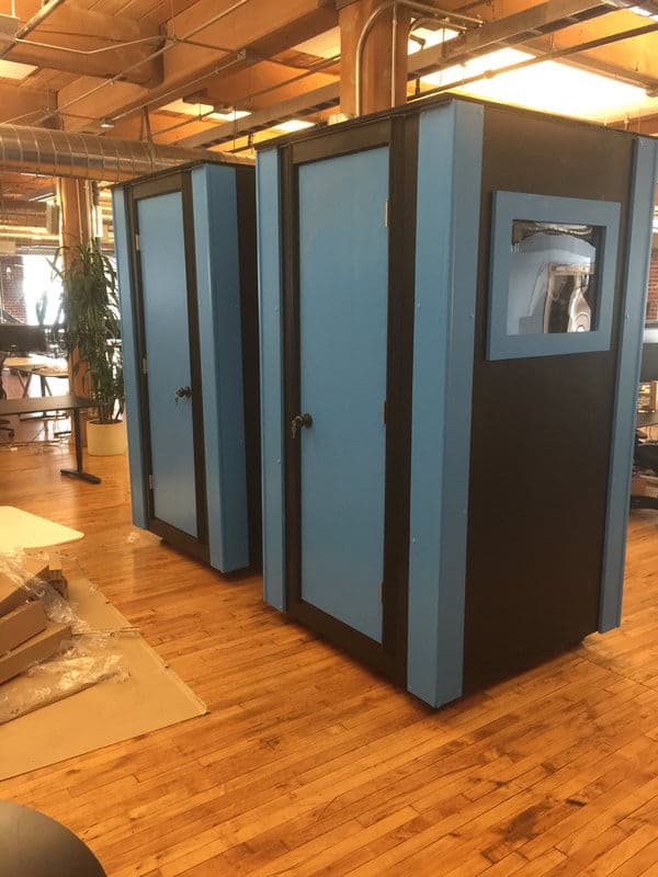 Dual blue privacy pods in a modern office space, featuring windows and black accents.