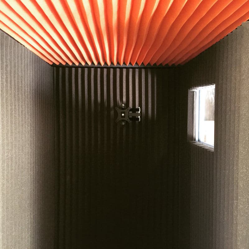 Interior of a soundproof booth featuring black and orange acoustic panels.