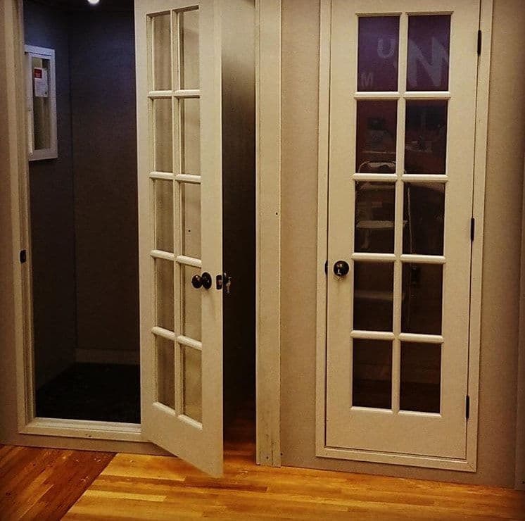 Double glass-paneled doors opening in a modern interior with wooden flooring and subtle lighting.