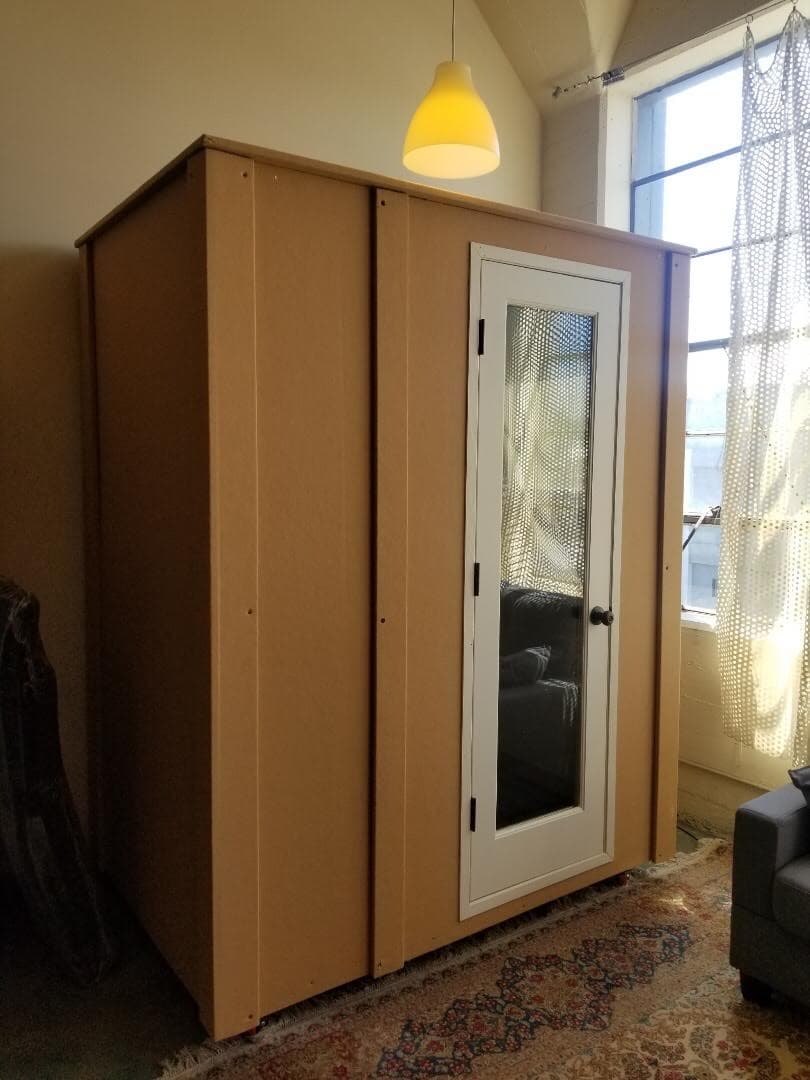 Modern pod-style office space with a clear door, located in a well-lit room.