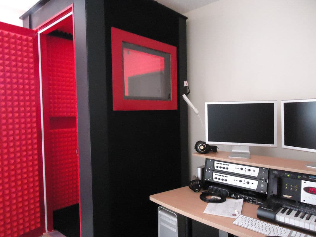 Home recording studio with soundproof booth, computer monitors, and music equipment.