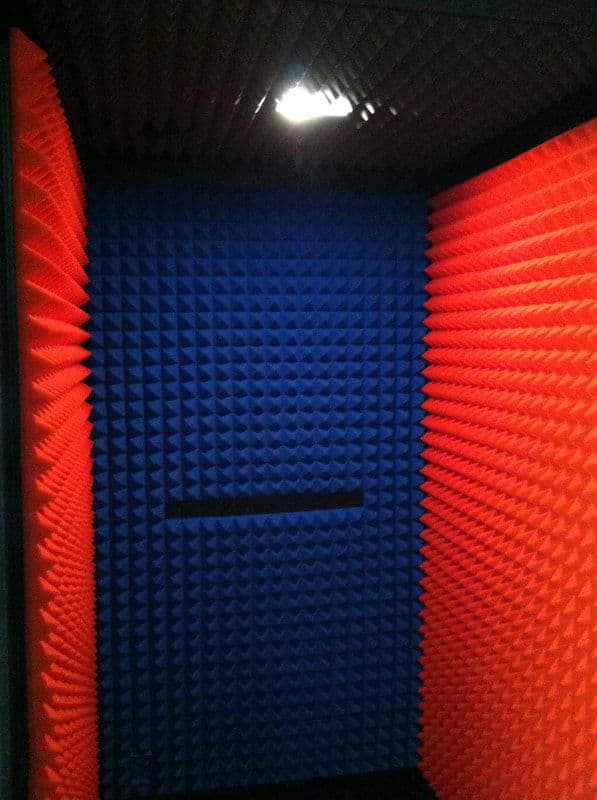Soundproof acoustic treatment with blue and red foam panels in a recording booth.