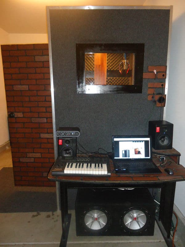 Home recording studio setup with keyboard, speakers, and soundproof booth.