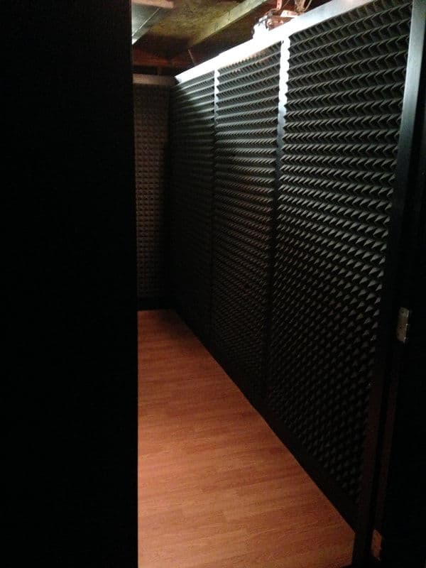 Soundproof room with acoustic foam panels and wooden flooring, ideal for recording or practice.