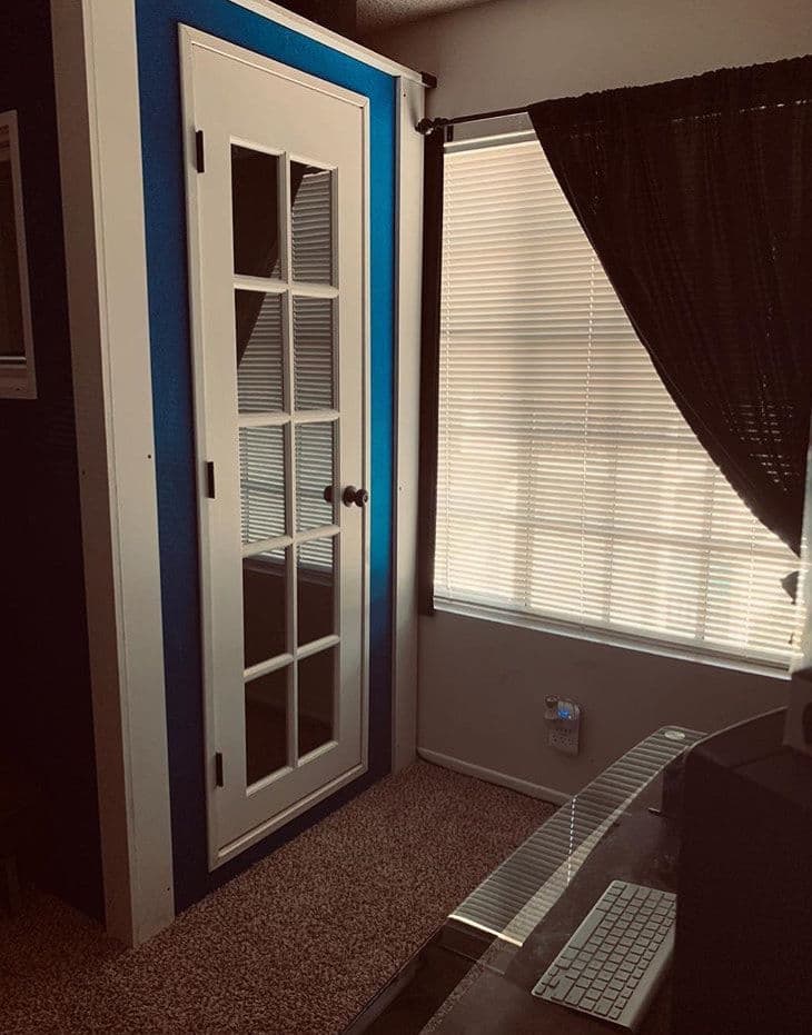 Interior view of a modern office space featuring a blue accent wall and a glass-paneled door.