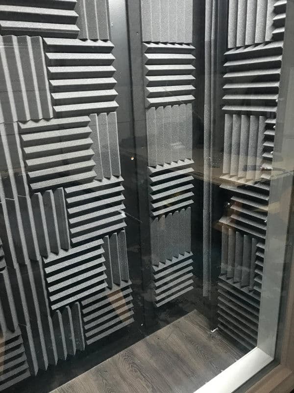 Soundproof recording studio with acoustic foam panels and wooden flooring.