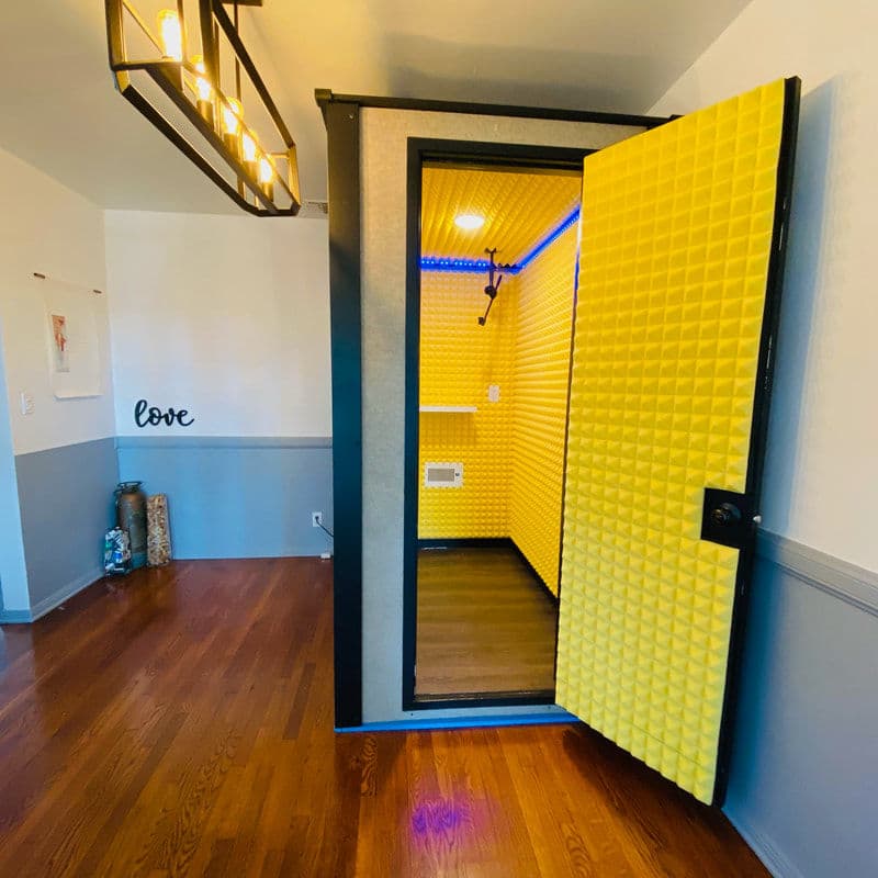 Soundproof recording booth with bright yellow acoustic panels in a modern home interior.