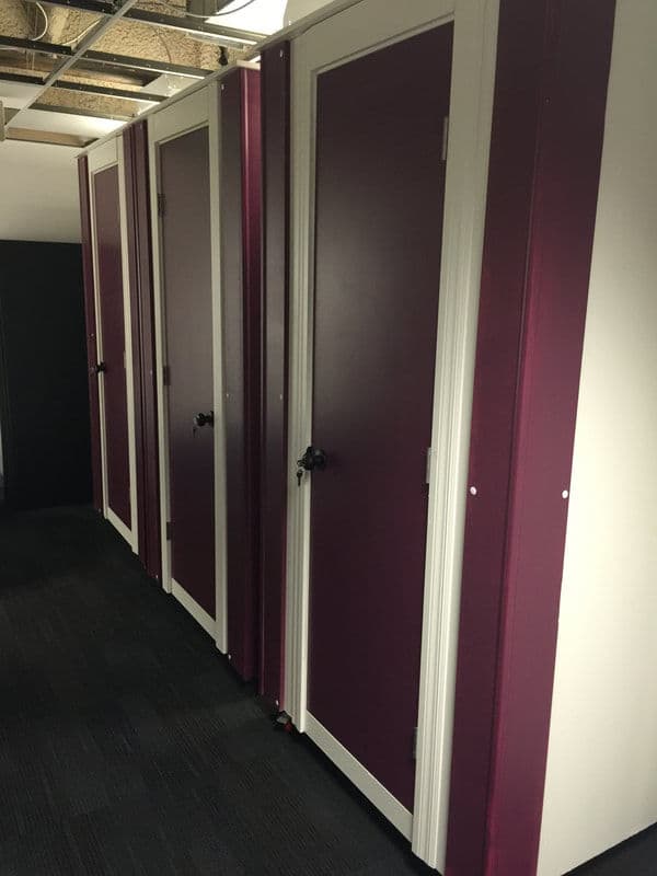 Series of purple and white storage unit doors in a modern hallway.