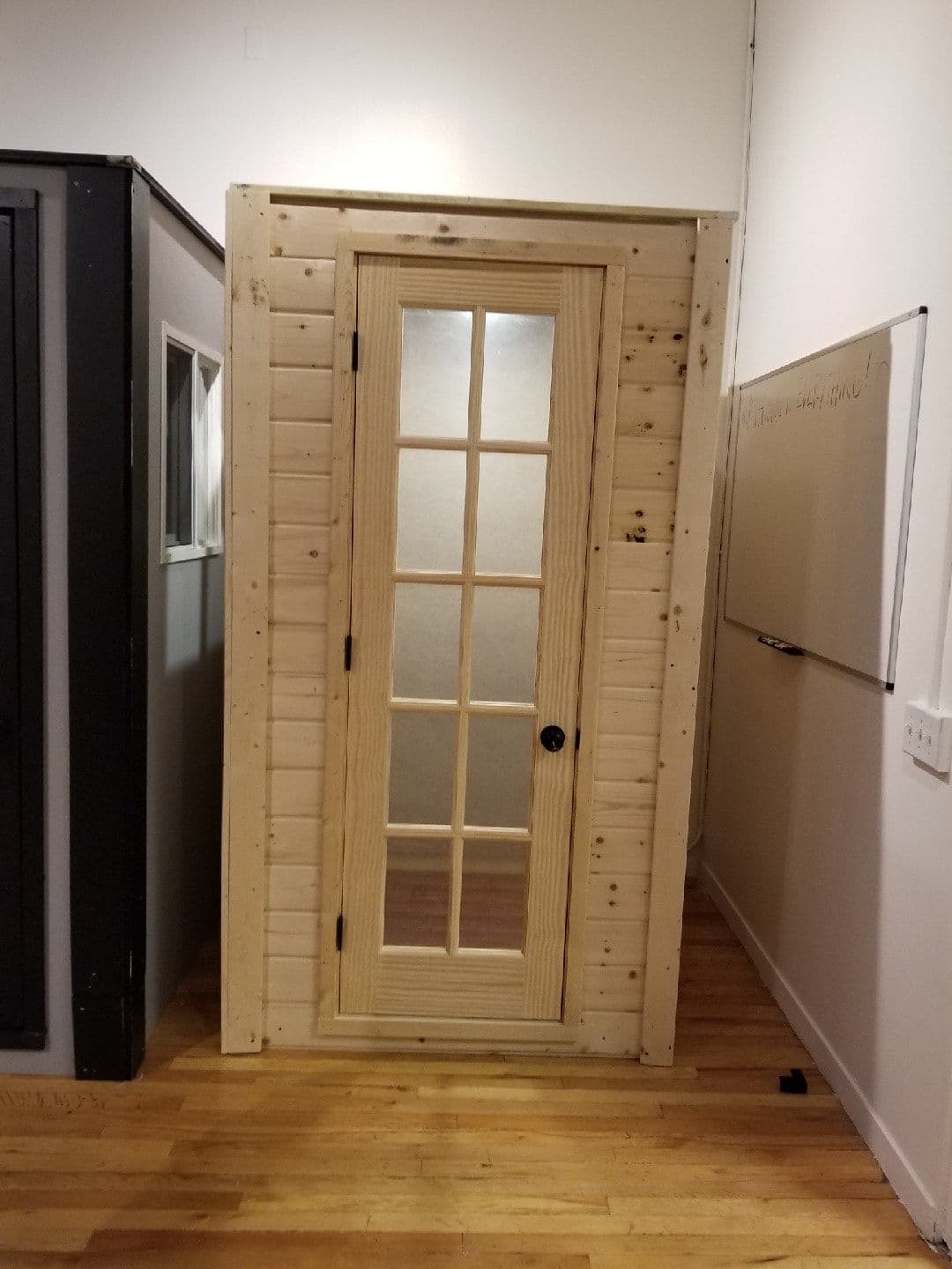 Interior wooden door with frosted glass panels in a modern room setting.
