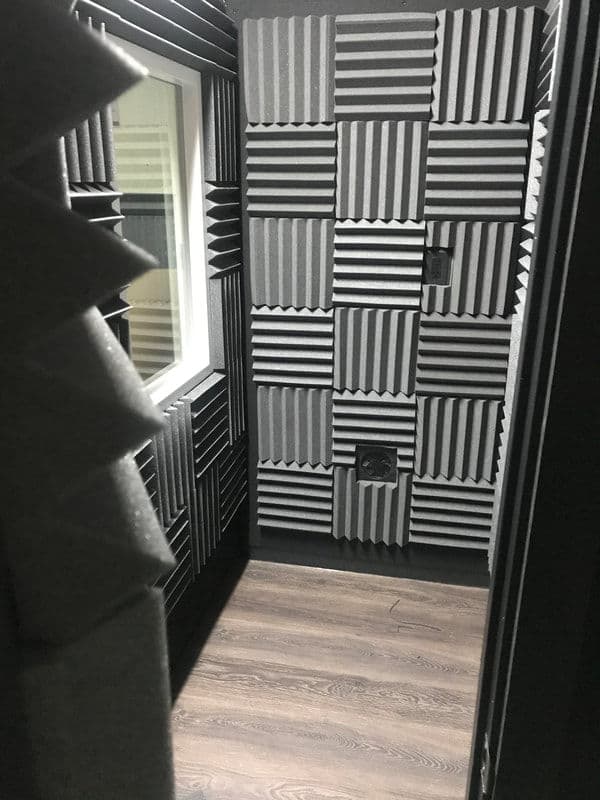 Soundproof recording studio booth with acoustic panels and wood flooring. Ideal for audio production.