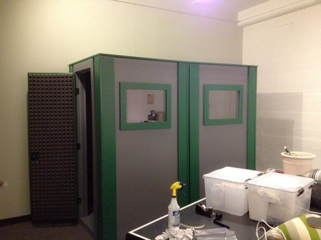 Soundproof recording booth with a gray and green design, featuring two windows.