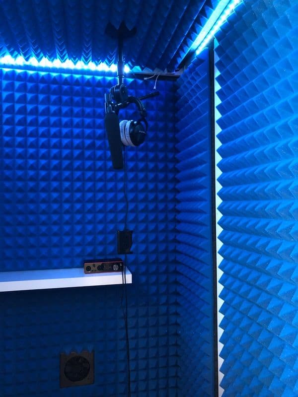 Soundproof recording studio with blue acoustic foam, microphone, and headphones.