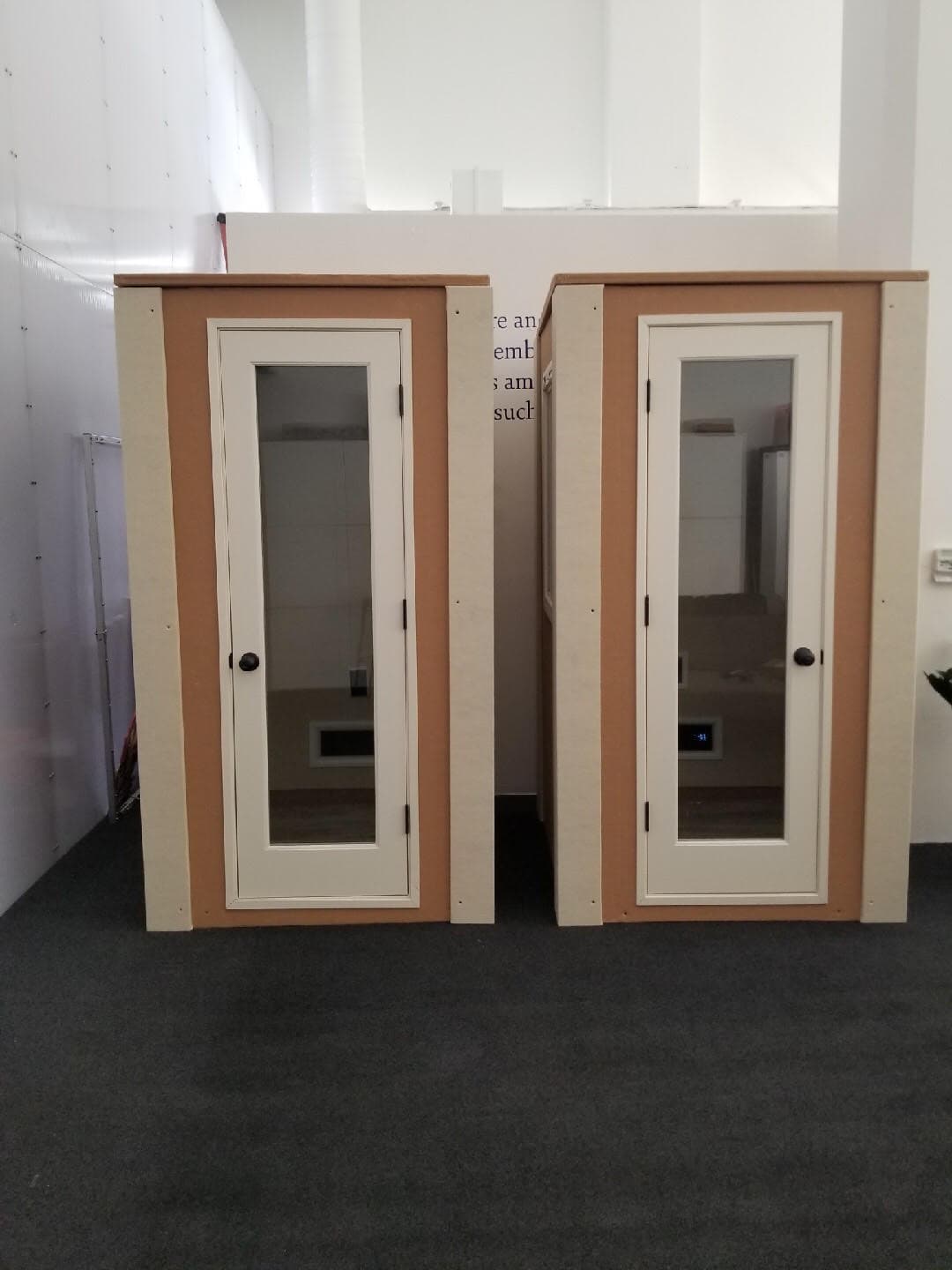 Two modern soundproof booths with glass doors in a minimalistic design.