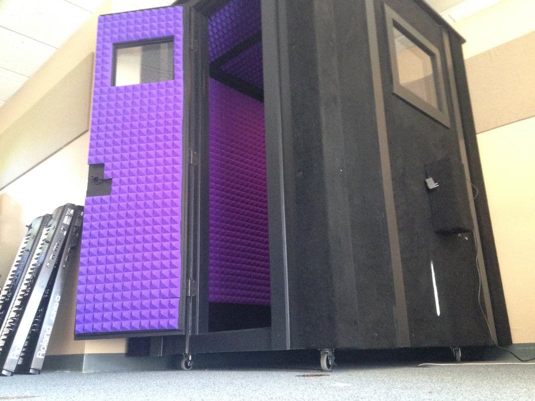 Soundproof vocal booth with purple acoustic panels and black exterior for recording.