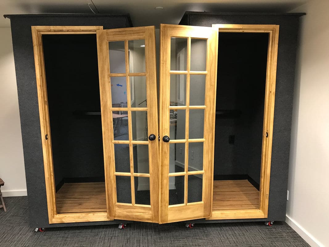 Modern soundproof booth with wooden double doors and glass panels, ideal for private calls.