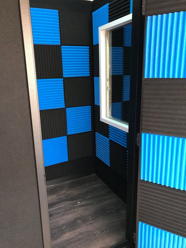 Soundproof recording booth interior with blue and black acoustic panels and a window.