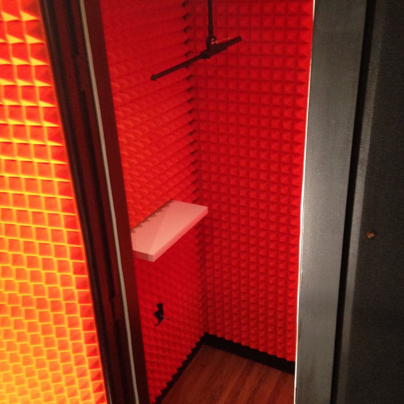 Soundproof recording booth with bright orange acoustic foam and minimalist design.