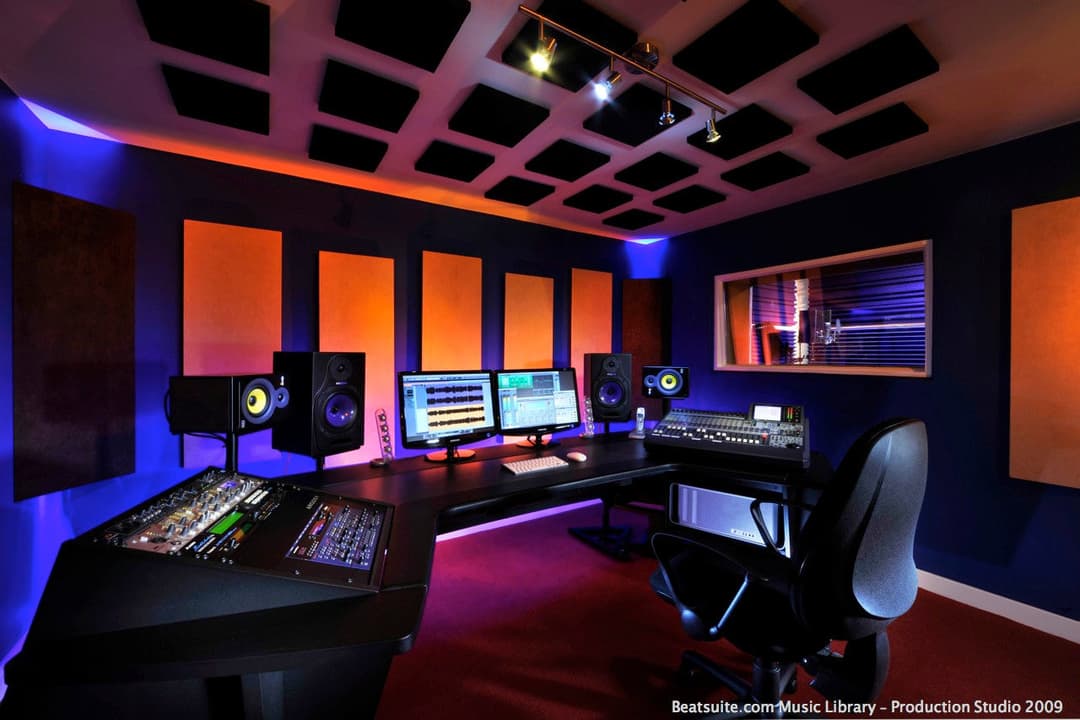Modern music production studio with dual monitors, mixing console, and acoustic paneling.