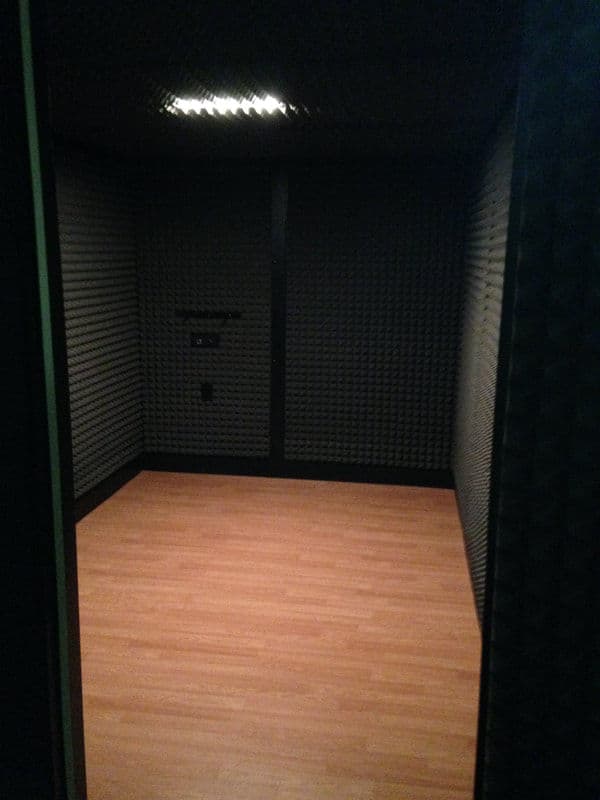 Soundproof recording studio with padded walls and wooden floor, spacious and minimalist design.