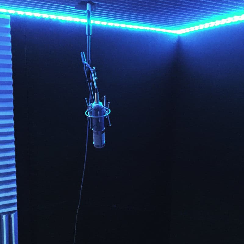 Recording studio with a microphone under blue LED lighting in a soundproof room.